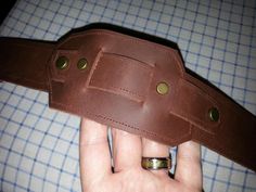 a hand holding a brown leather belt