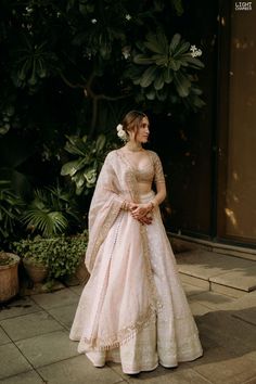 a woman in a pink gown standing on the sidewalk with her hands clasped to her chest