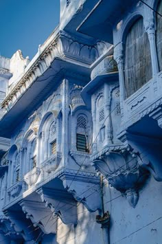 an old blue building with many windows and balconies on the outside, against a bright blue sky