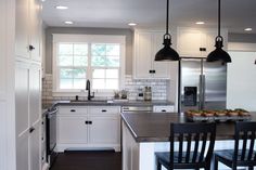 a kitchen with white cabinets and black chairs