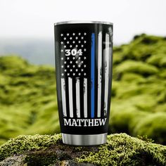 a blue line coffee cup sitting on top of a moss covered rock with the american flag painted on it