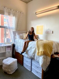 a woman sitting on top of a bed in a bedroom next to a large window