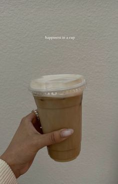 a woman holding up a cup of coffee with the words happiness in a cup above it