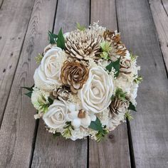 a bridal bouquet with white flowers and pine cones