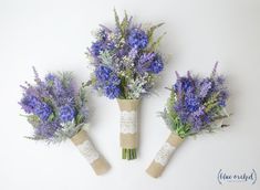 three bouquets of blue flowers in burlock wrapped vases on a white background