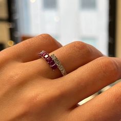 a woman's hand with a diamond and ruby ring on top of her finger