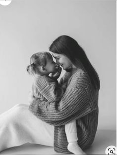 black and white photograph of two women sitting on the floor holding a baby in their arms