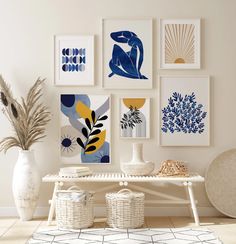 a white table topped with vases filled with flowers next to pictures on the wall