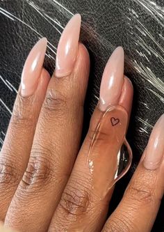 a woman's hand with long, shiny nails and a heart shaped ring on it