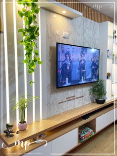 a flat screen tv sitting on top of a wooden shelf in a living room next to a potted plant