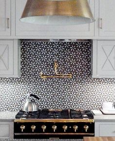 an image of a kitchen with white cabinets and black tile backsplash tiles on the stove