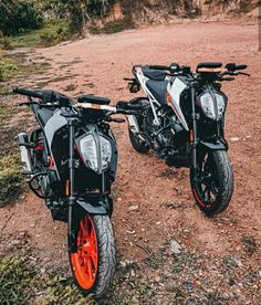 two motorcycles parked next to each other in the dirt