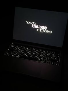 an open laptop computer sitting on top of a black table with the words how to kiss a guy in 10 days written on it