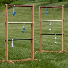 two wooden racks with balls hanging from them in the middle of a grassy area next to some trees