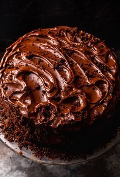 a cake with chocolate frosting on top of it sitting on a glass platter