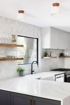 a kitchen with marble counter tops and wooden shelves on the wall, along with open shelving