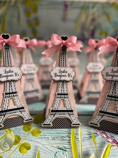 pink and black paris themed place card holders with bows on each side, sitting in front of the eiffel tower