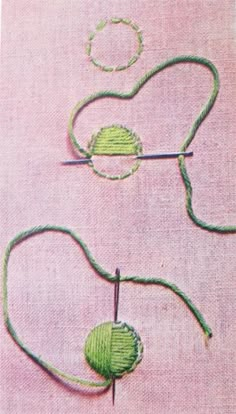 two green yarns are being stitched together on a pink surface with scissors and thread