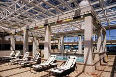 lounge chairs are lined up in front of an indoor swimming pool