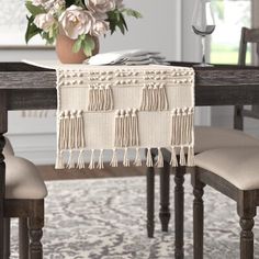 a dining room table with a vase and flowers on top of it next to a chair