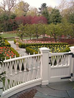 a white fence surrounded by flowers and trees