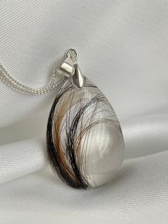 a white and black pendant with some hair on it