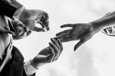 several people reaching out their hands to touch each other's fingers in black and white