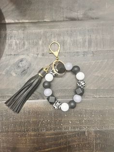 the black and white beaded bracelet with tassel is hanging on a wooden surface