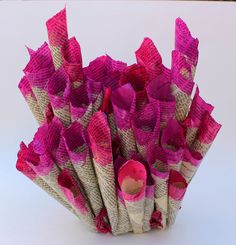 a bunch of pink and white paper flowers on a white tablecloth covered vase with one flower in the middle