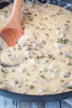 a wooden spoon in a skillet filled with cheese sauce