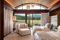 a bedroom with two beds and chairs in front of a large glass door that leads to a balcony