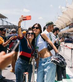 two women taking a selfie while standing next to each other in front of a crowd