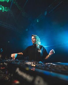 a woman with blue hair is playing music on a dj's mixer at a concert