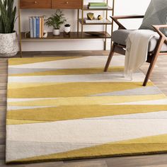 a living room area with a chair, book shelf and rug on the wooden floor