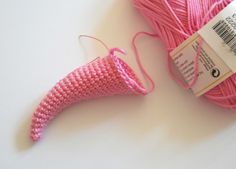 a ball of pink yarn next to a spool of thread on a white surface