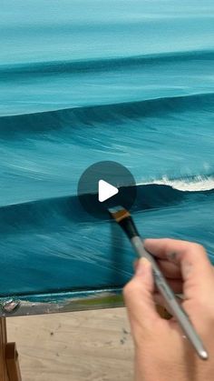 someone is painting an ocean scene on the easel with their thumbnails and holding a paintbrush