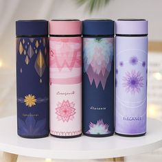 four different types of travel mugs sitting on a white table next to each other