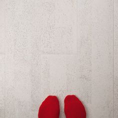 a pair of red slippers sitting on top of a white tile floor next to a wall