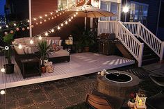 an outdoor deck with patio furniture and string lights