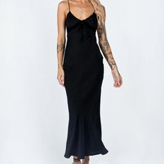 a woman is wearing a black dress and has tattoos on her arm, while standing in front of a white background