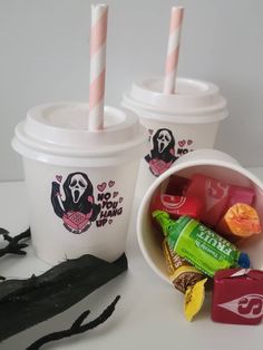 two cups filled with candy next to each other on a white counter top, one has pink and white straws in it