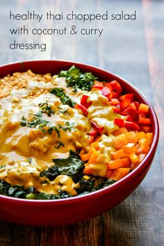 a red bowl filled with different types of food on top of a wooden table and the words healthy that chopped salad with coconut & curry dressing