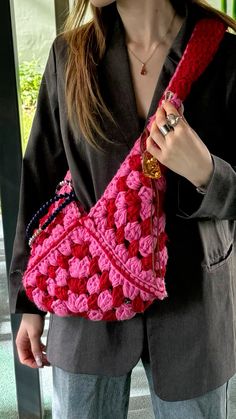 a woman is holding a pink crocheted purse