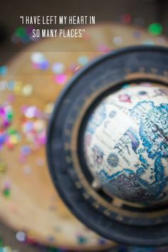 a small globe sitting on top of a wooden table with confetti around it