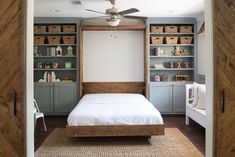 a bed sitting inside of a bedroom next to a closet filled with bookshelves