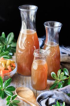 three pitchers filled with liquid sitting on top of a wooden table next to other items