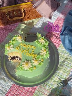 a green cake sitting on top of a table next to a basket and purses