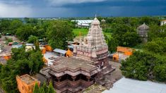 an aerial view of a temple in the middle of trees and buildings, with dark clouds overhead