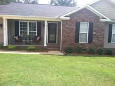 a brick house with black shutters and green grass