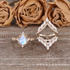 three different rings sitting next to each other on top of a wooden table with roses in the background